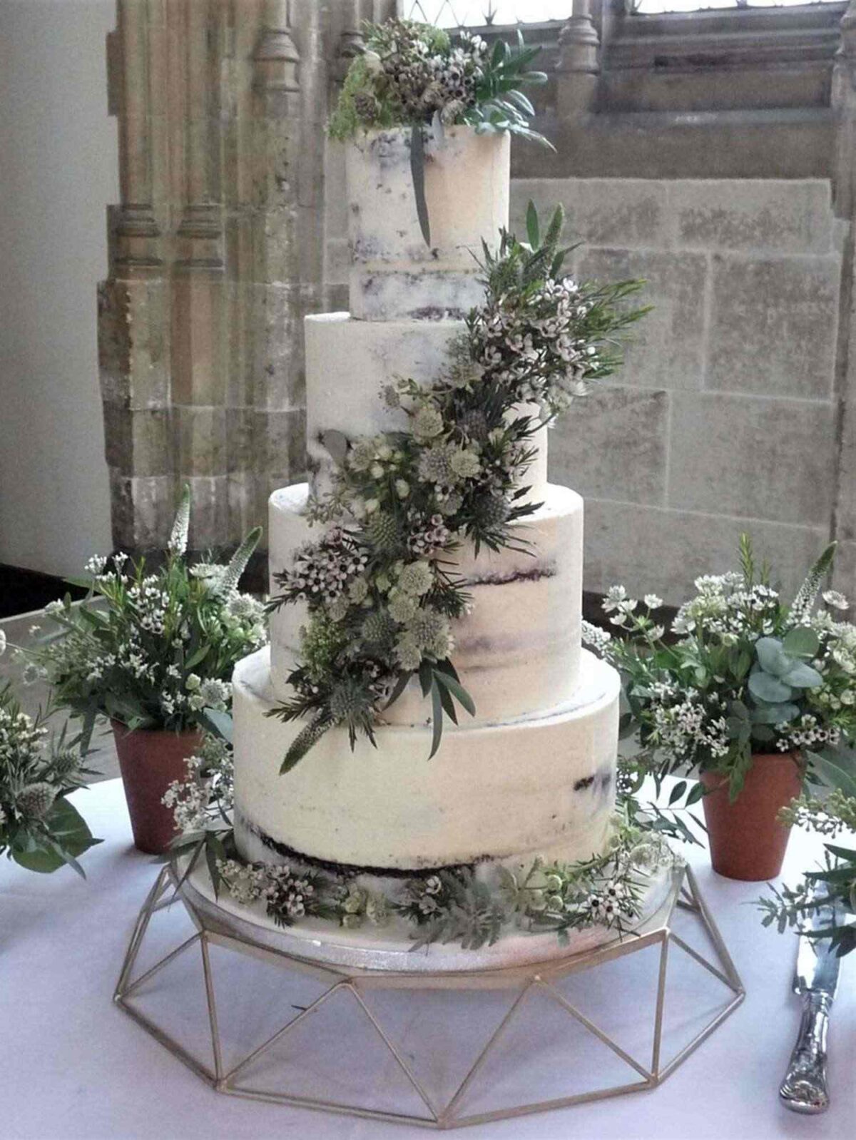 tiered cake with buttercream frosting and fresh greenery decoration