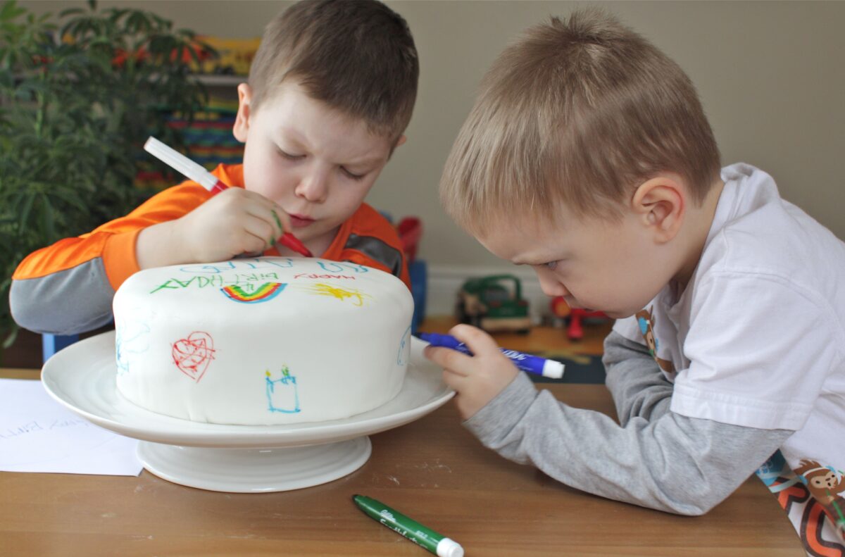 Kids do coloring on a cake